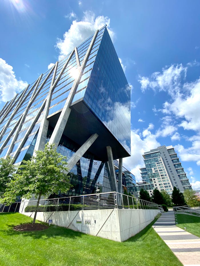 pexels-photo-19157998 A sleek modern office building with glass facade, captured under a bright blue sky.