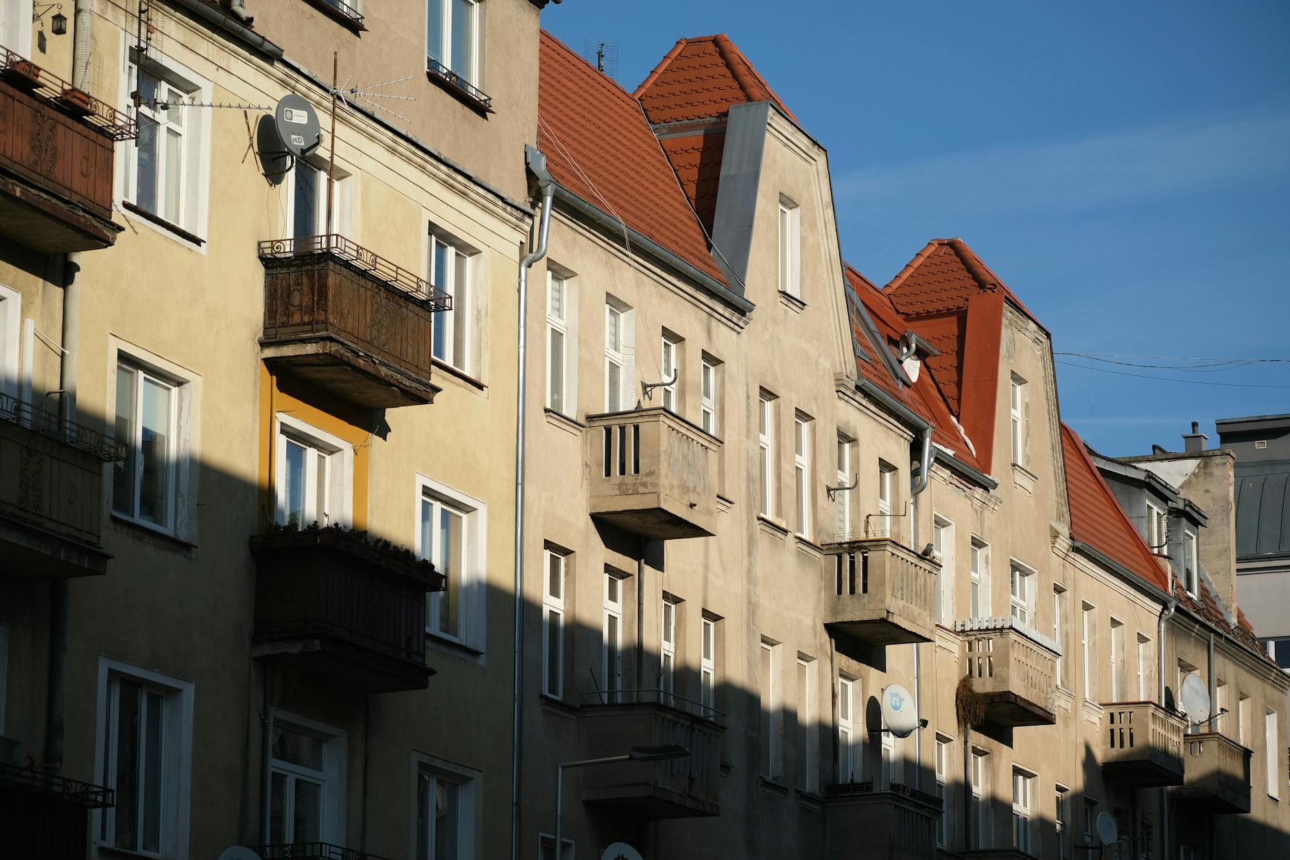 Classic European apartment building with red rooftops and balconies, captured in natural daylight.